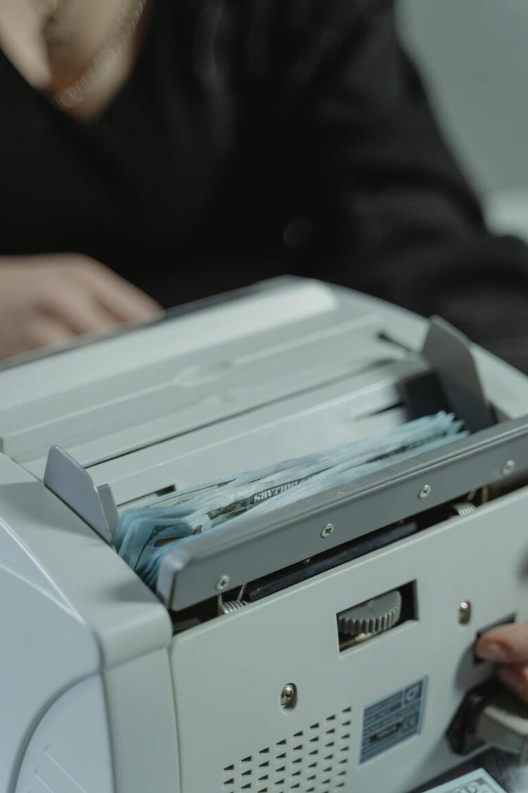 Close-up shot of a money counting machine with bills being processed indoors.